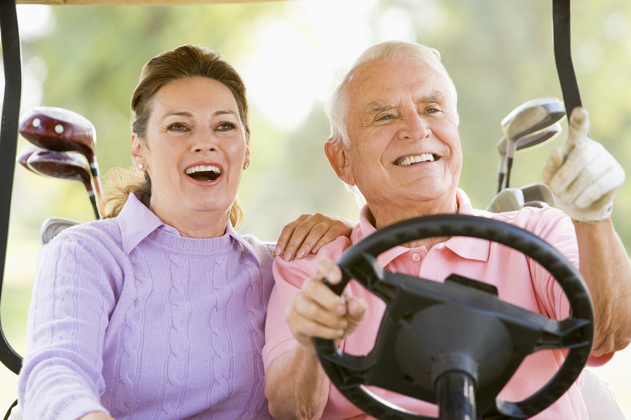 couple enjoying golf on a cart smiling