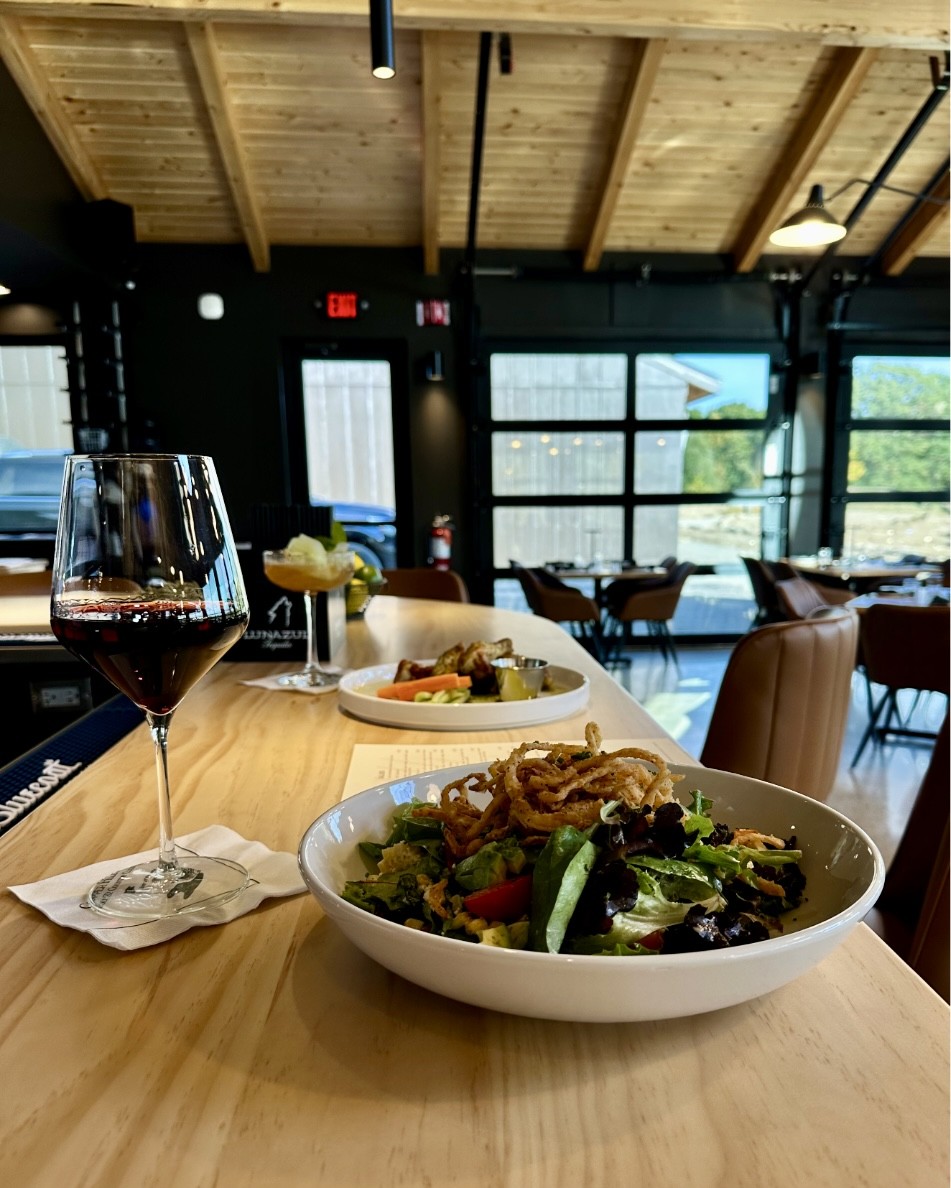 Restaurant with a wine glass and salad ona bar with tall ceilings the copper club doors opening to golf course views